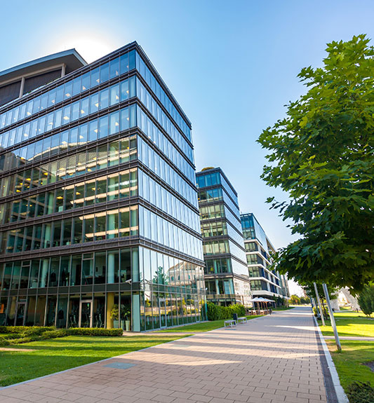 A glass office building by a brick sidewalk